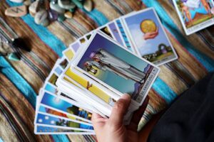 A close-up of a person holding tarot cards for a reading on a textured cloth.